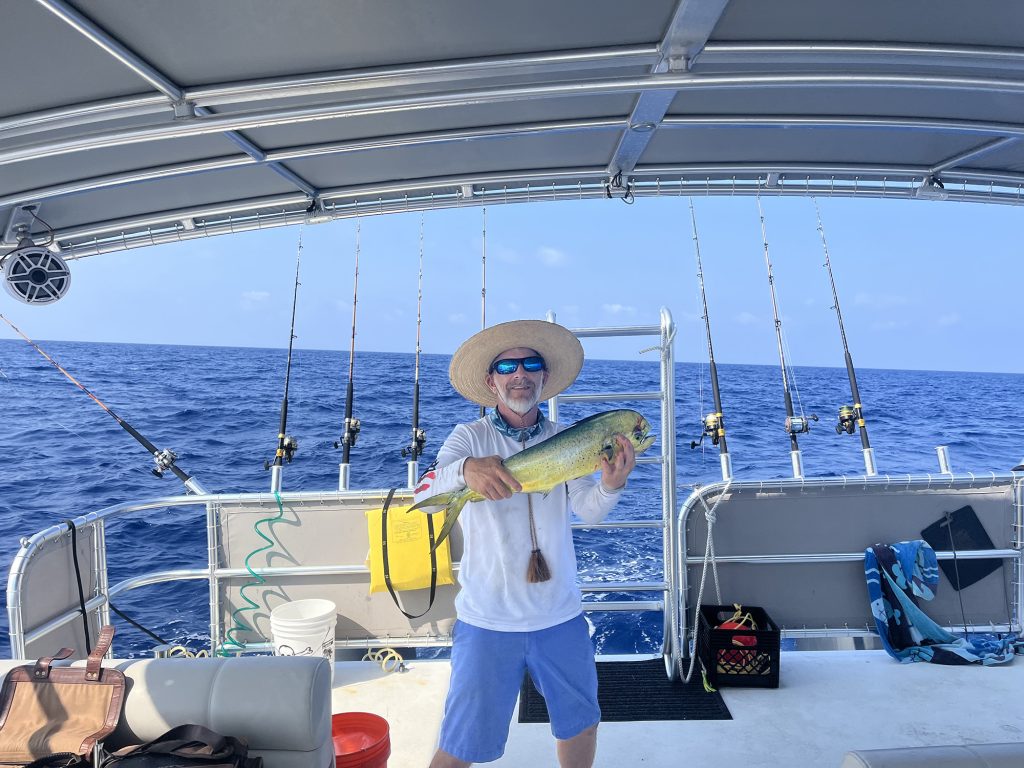 A man on a boat proudly display a large fish they caught during their fishing trip.