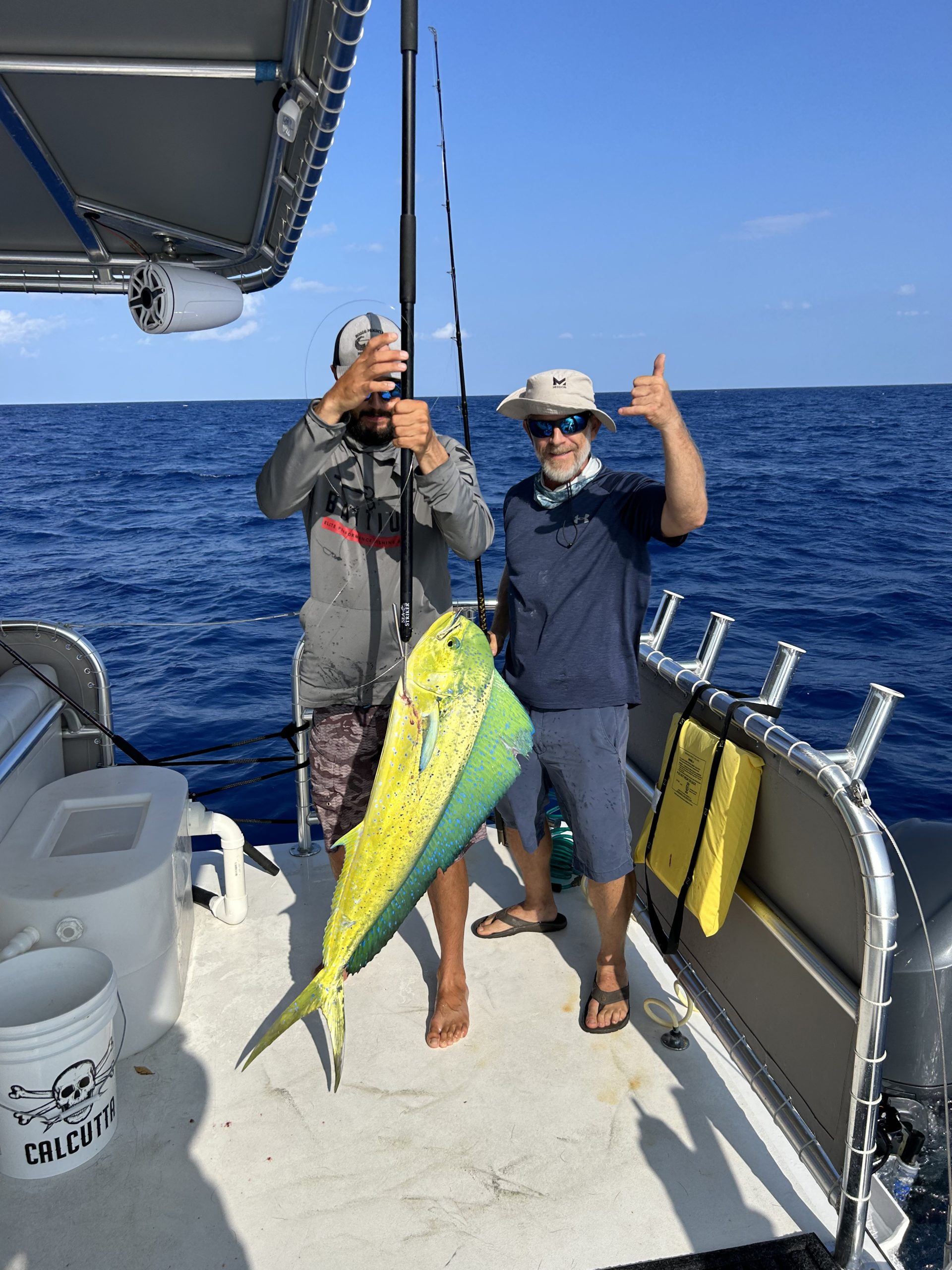 Two men on a boat proudly display a large fish they caught