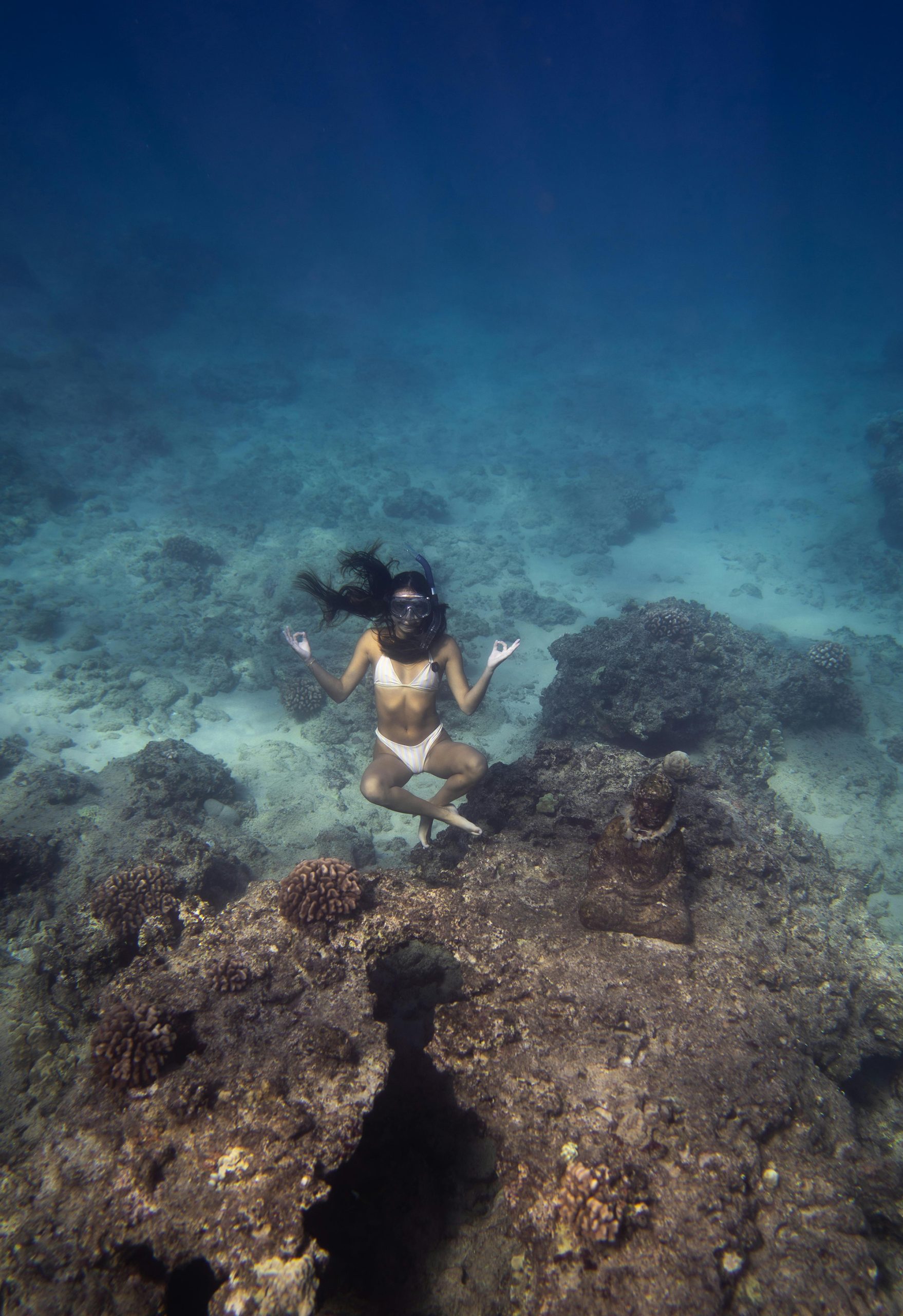 A woman wearing a bikini relaxes on a rock under sea water on Custom Catch Charters ocean adventure