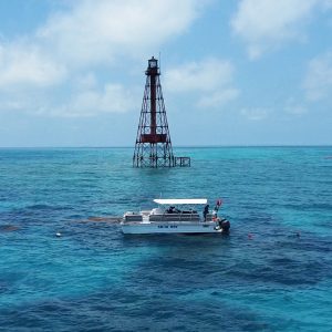 A boat floats in the water near a tall lighthouse