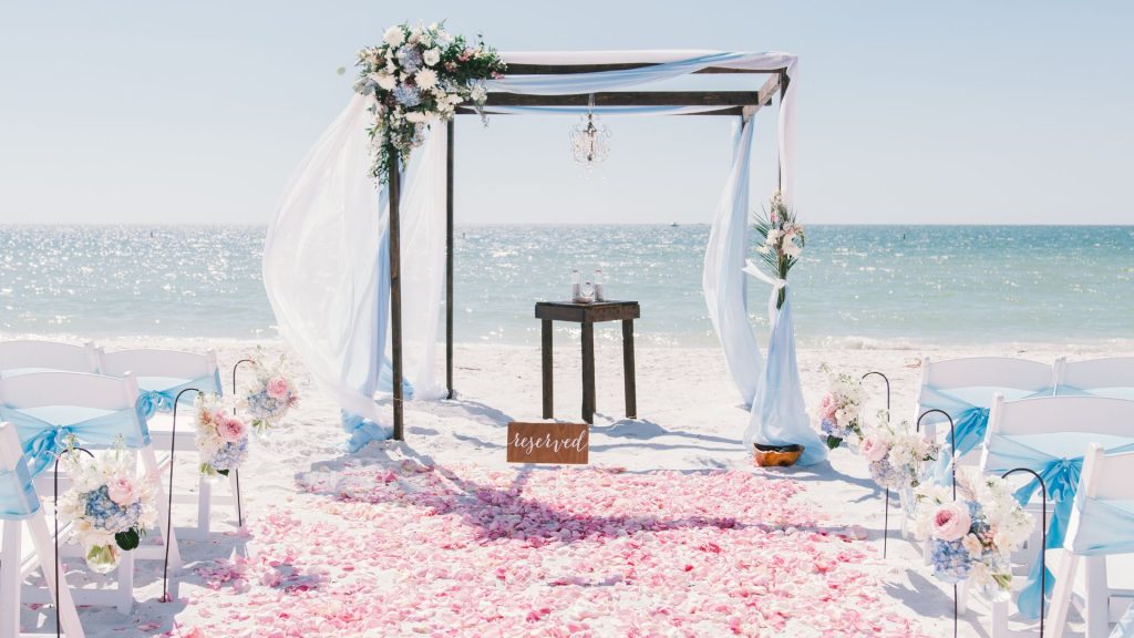 Florida Keys beach wedding ceremony with floral arch, ocean backdrop, and white sand decor